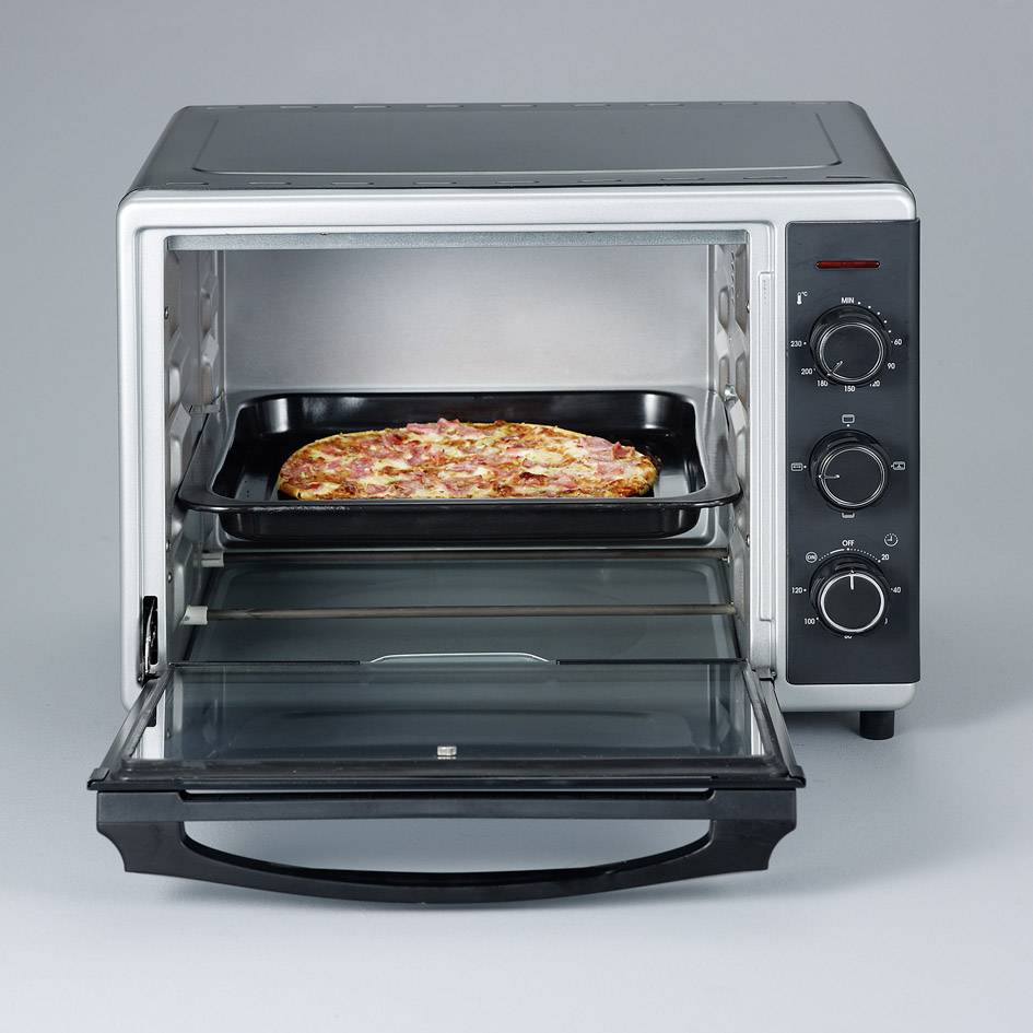 A small oven with an open door. A pizza is sitting on a baking tray inside and is being baked. The control panel is visible on the right.