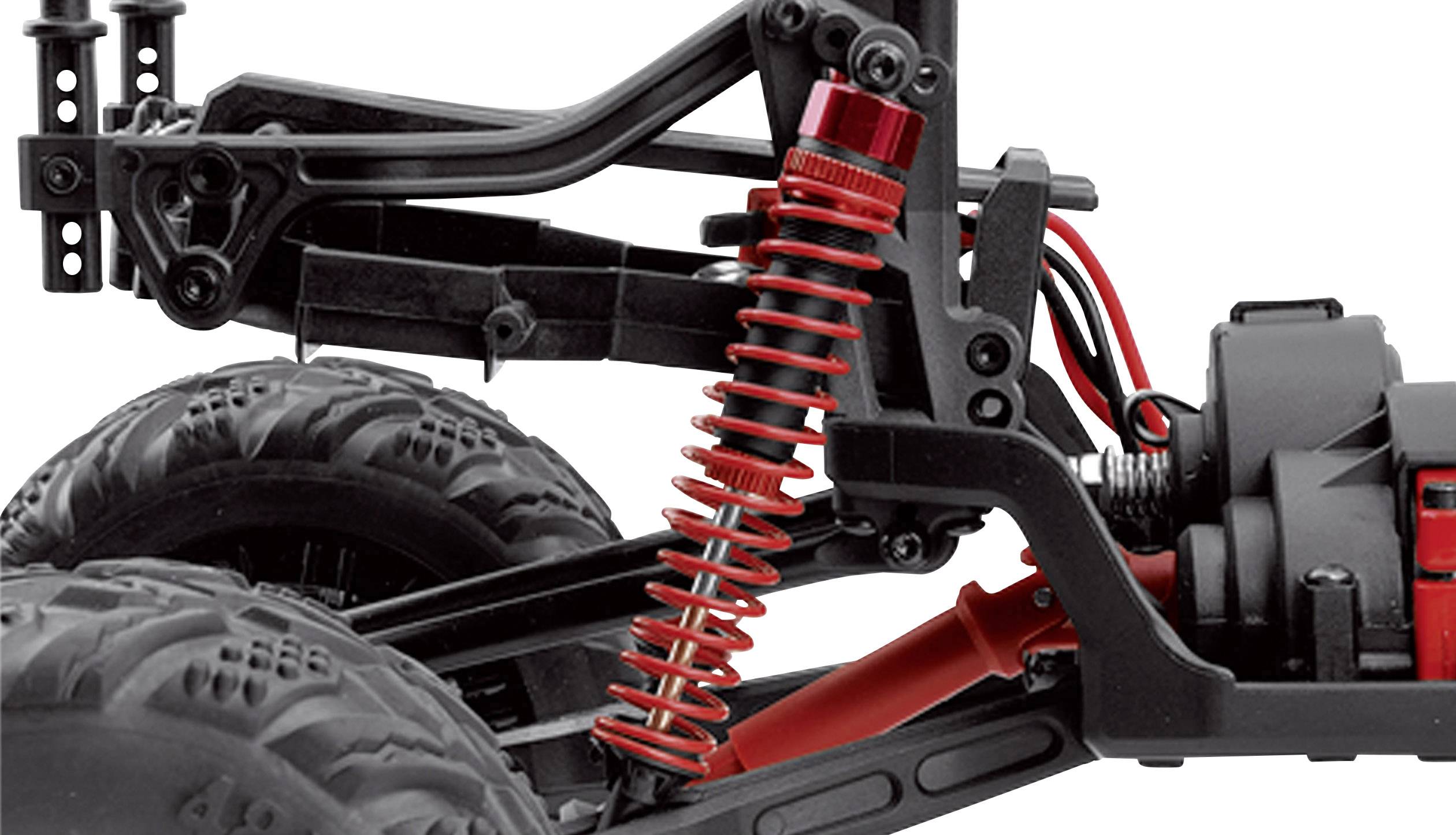 Close-up of a red shock absorber on a remote-controlled car, showing the suspension and wheel in the background.