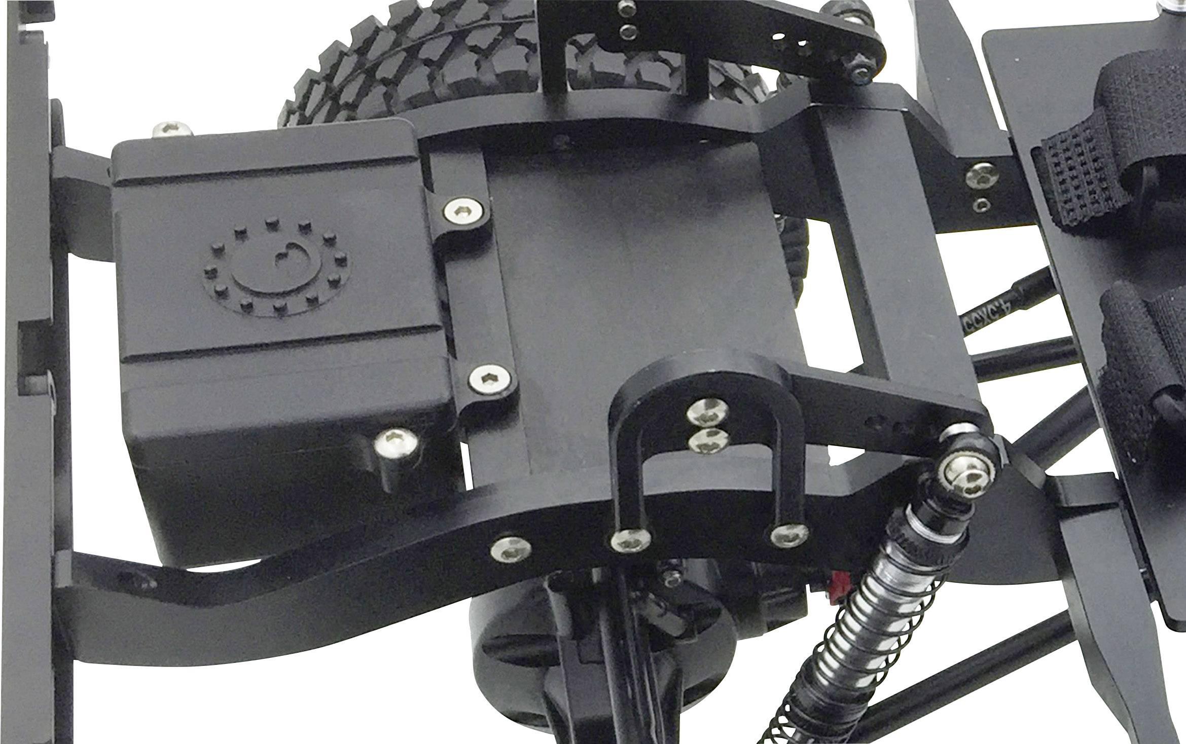 Close-up of an RC car chassis with visible suspension, drive shaft, and tyres. Detailed view of mechanical components.