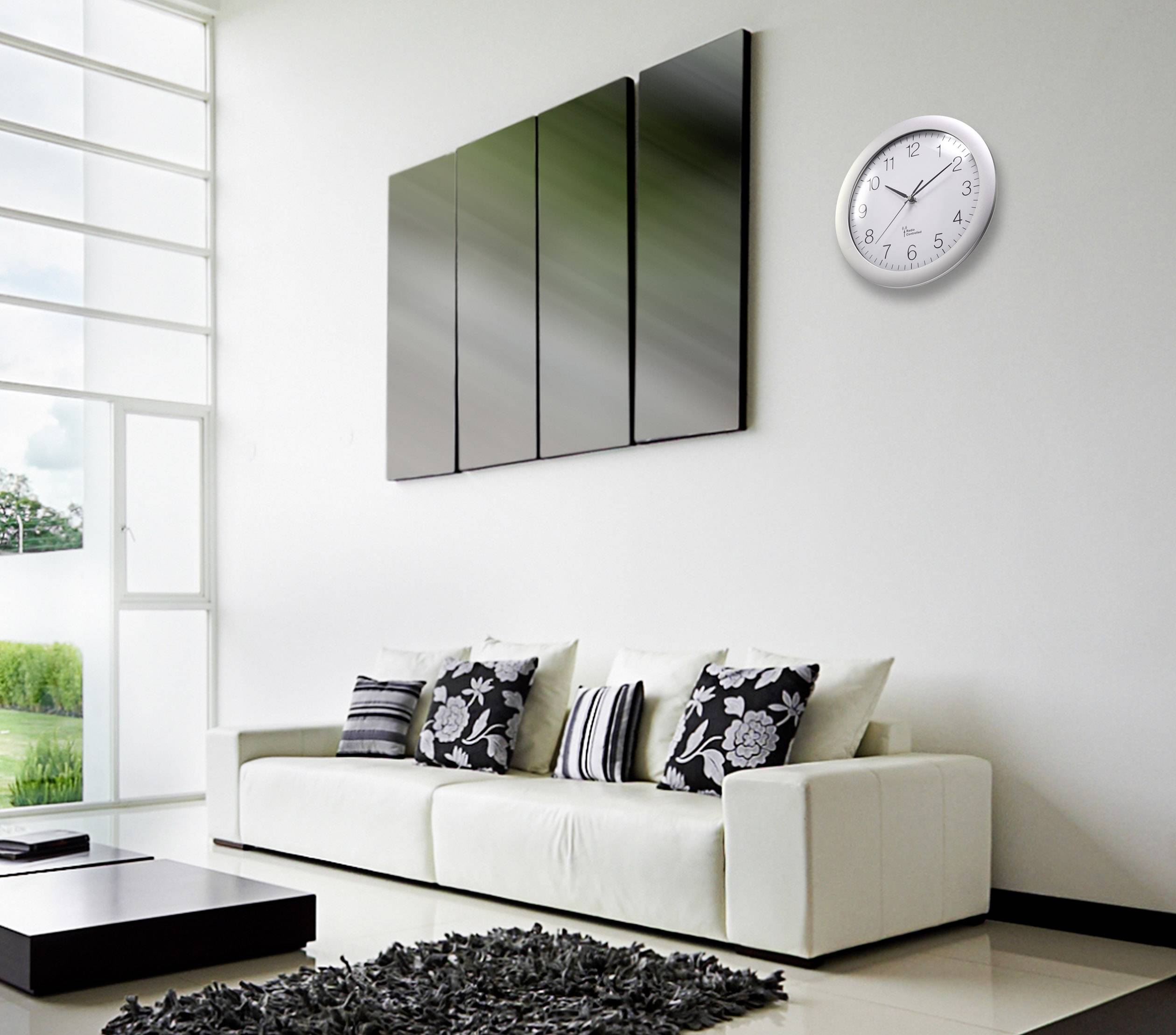 A modern living room with a white sofa, decorative cushions, an abstract wall painting and a round wall clock.