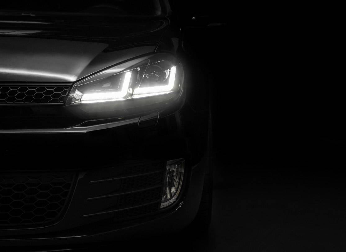 Car in the darkness, headlights shining brightly forward, half of the vehicle visible.