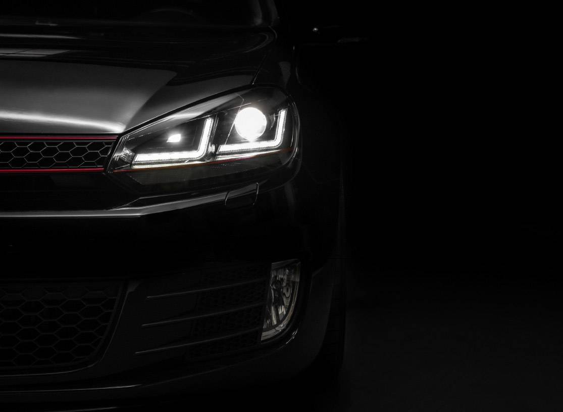 Car with headlights on against a black background.
