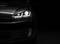 Car with headlights on against a black background.