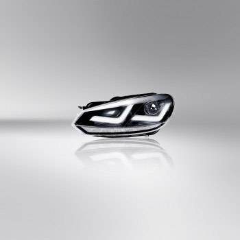 A modern headlight design in a bright studio. The headlight has a distinctive, curved shape with LED elements.