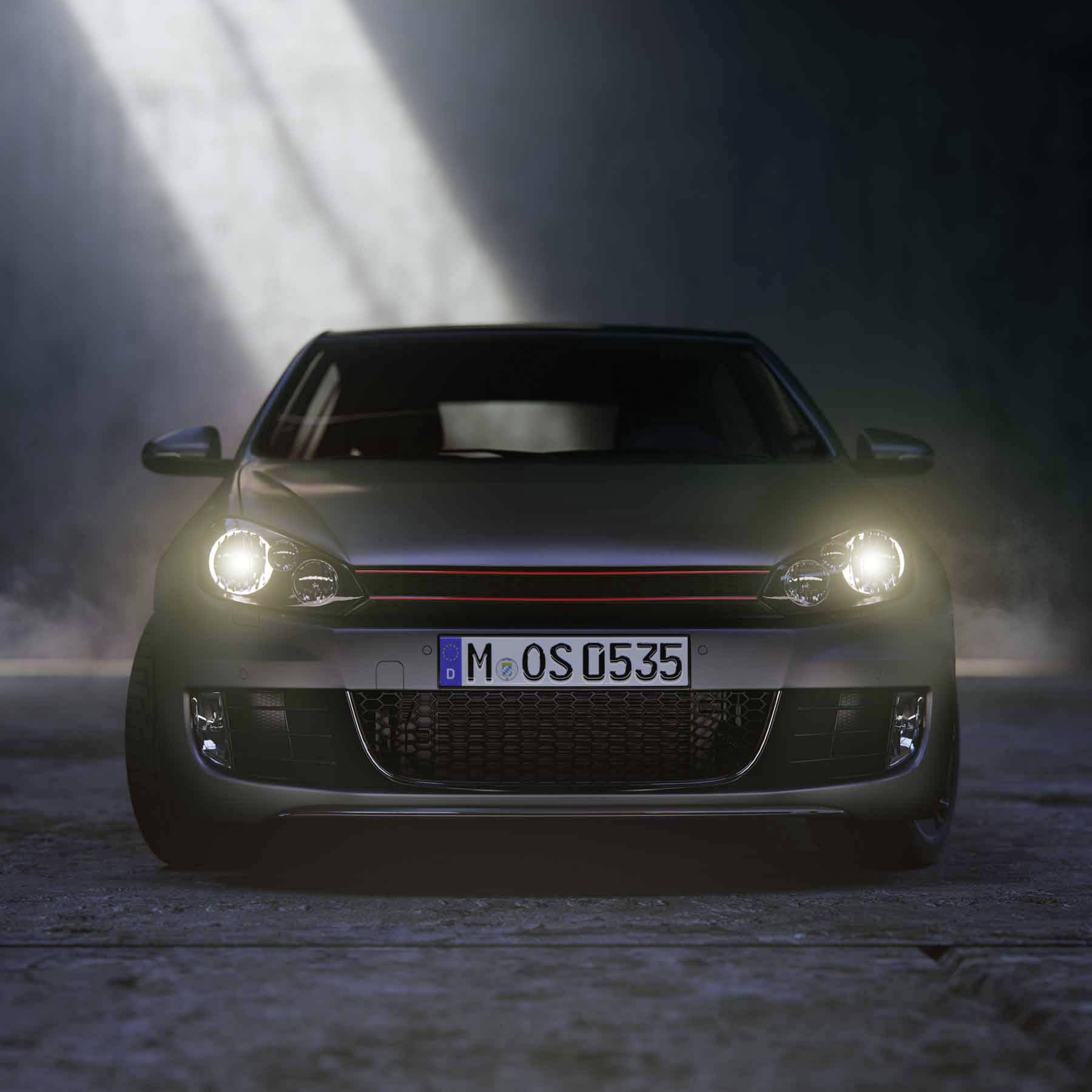 A car is parked head-on in a car park within a dark, misty environment. Headlights are illuminated, number plate visible.