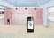 A smartphone displays an app for room measurement via Bluetooth, in a room with empty frames on pink walls.