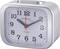A silver alarm clock with an analogue dial shows the time as 10:10. Black hour and minute hands, with a red second hand.