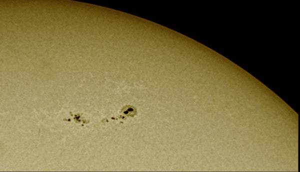 The image depicts the solar surface with a group of sunspots. These dark spots are cooler than the surrounding areas.