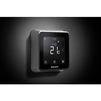 A digital thermostat on the wall displays a temperature of 21 degrees Celsius. It has a modern, square shape.