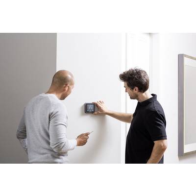 Two men against a white wall, one adjusting a digital thermostat, the other holding a notebook.