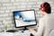 A person wearing red headphones is working at a desk and looking at a screen image of a snowboarder in snow-covered mountains.