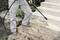 A person is cleaning the dirty stone steps outside using a pressure washer. Leaves and dirt are being removed.