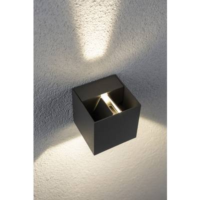 Wall lamp made from a black metal cube casts light upwards and downwards along a white wall, creating elegant lighting effects.