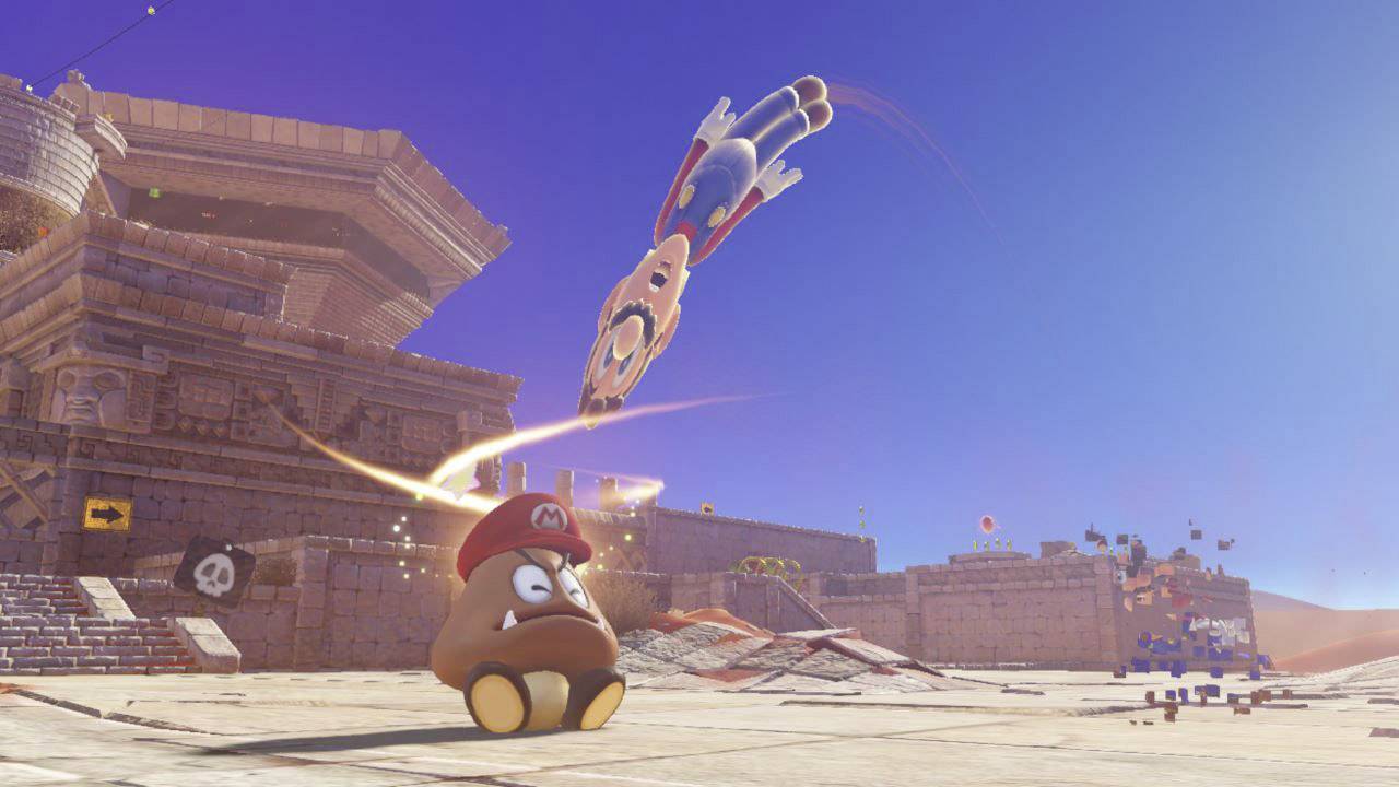 A Goomba wearing a cap jumps in front of a desert with ancient ruins. Mario can be seen being catapulted into the air.