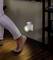 A person walks at night in a dark room. A night light with a motion sensor illuminates the floor.