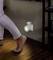 A person walks in a dark room; a night light with a motion sensor illuminates the floor and lights the way.