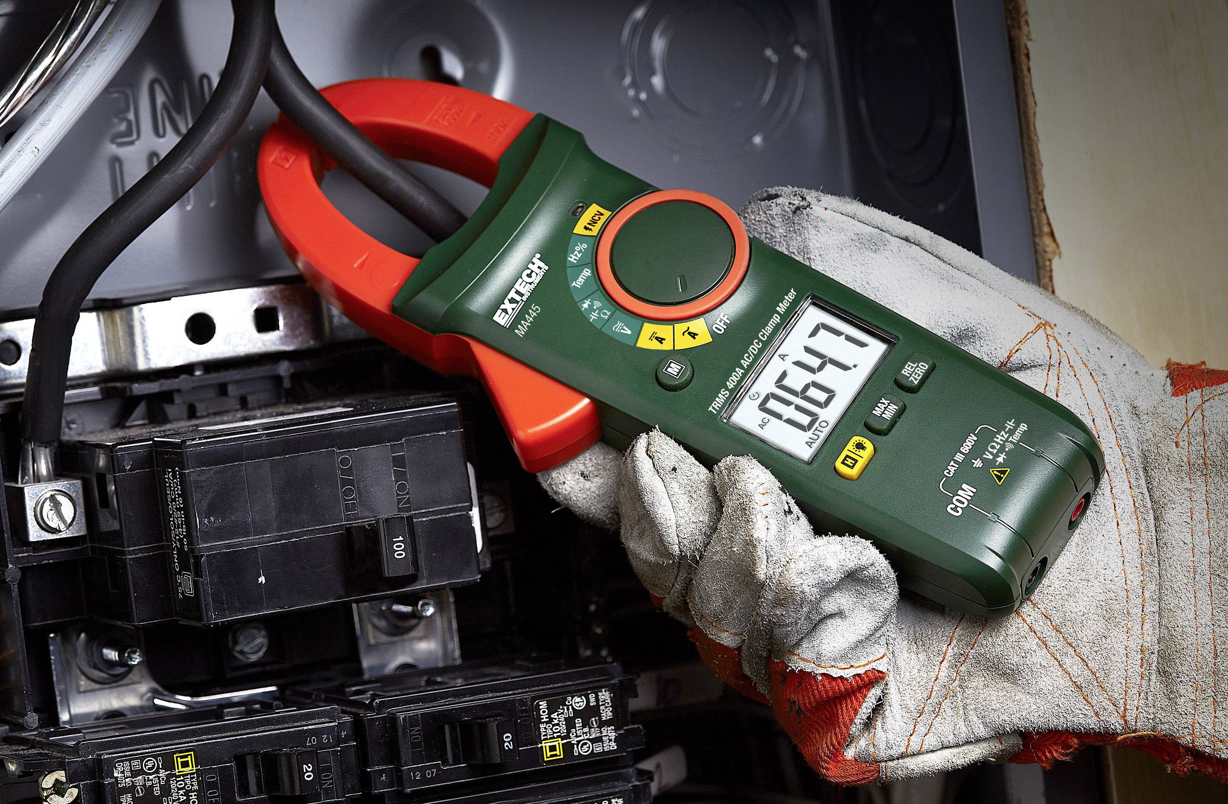 A digital ammeter is being used to measure the electrical current in a control cabinet. The displayed value is 164.7.