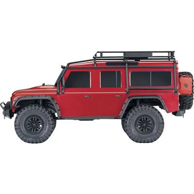 A red off-road vehicle with large tyres, set against a white background. The vehicle has side bars and a roof rack.
