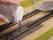 Hand scatters model railway ballast on miniature rails to create a realistic environment for a model railway layout.