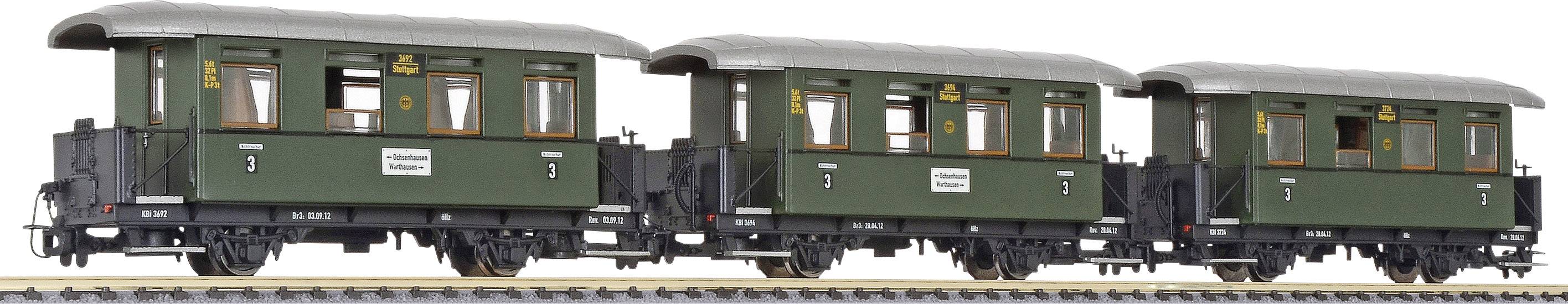 A green historical train with three carriages on a railway track.