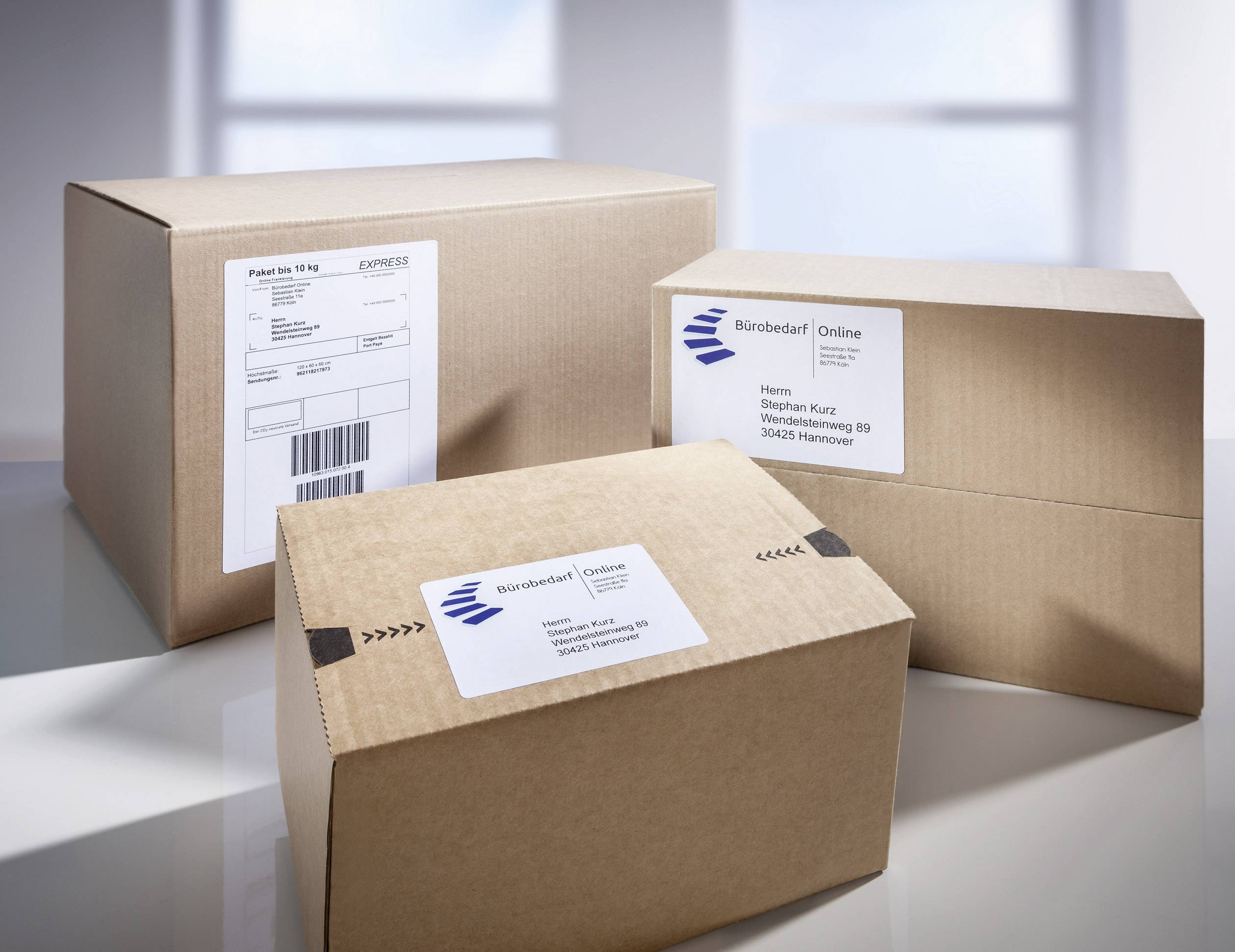 Three parcels with address labels standing on a table. The middle parcel bears the inscription 'Office Supplies Online'.