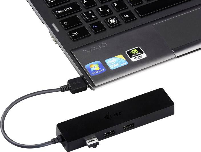 A black USB hub is connected to a laptop. The laptop displays several stickers with the logos of Windows, Intel and Nvidia.