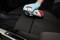 A person wearing gloves is spraying cleaner from an aerosol can onto a car seat to clean or maintain it.
