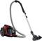 A red vacuum cleaner with a long suction tube and black floor nozzle stands upright.