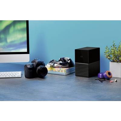 A desk with a camera, external hard drive, plants, and computer; shows a creative workspace.