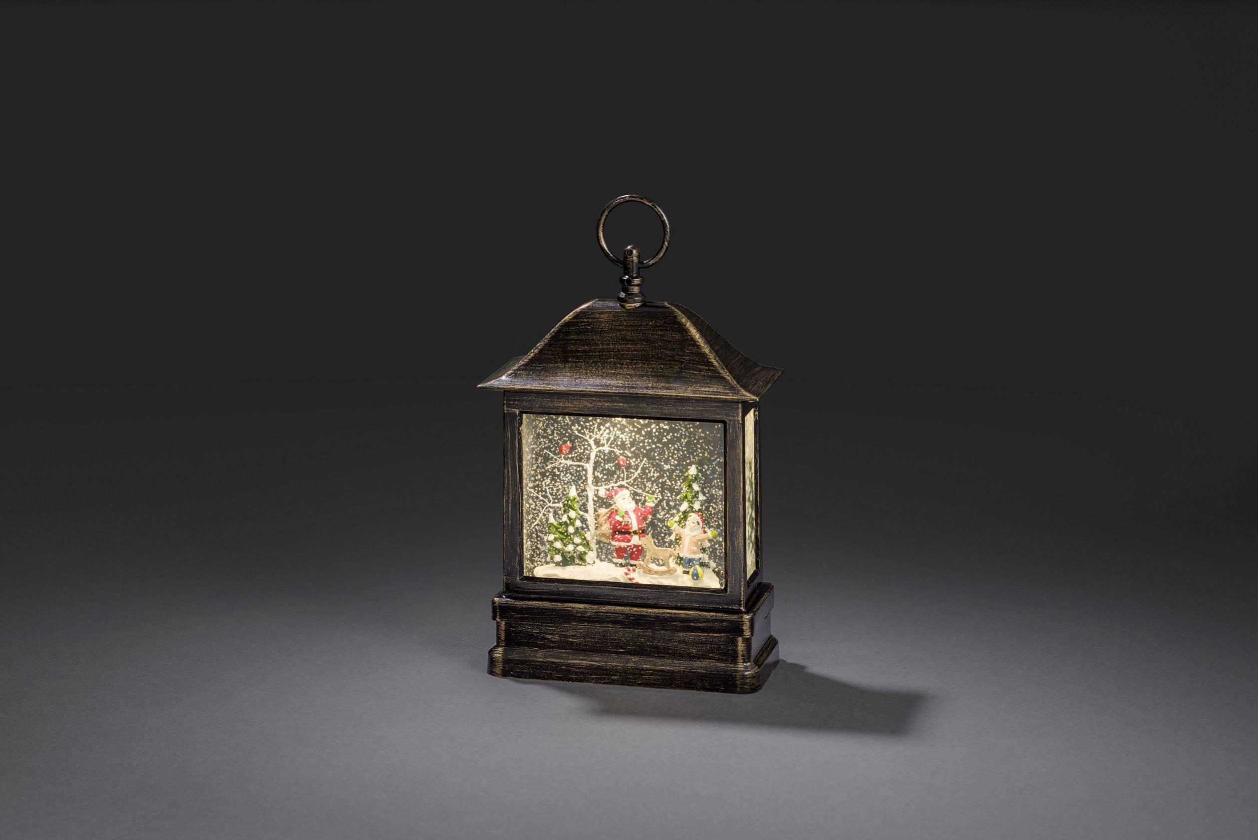 A snow lantern with a Father Christmas inside, surrounded by snow-covered trees and glittering snowflakes.