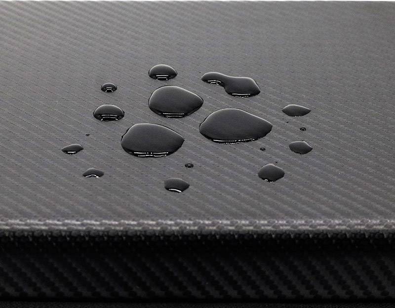Water droplets on a textured, dark surface that is likely water-repellent.