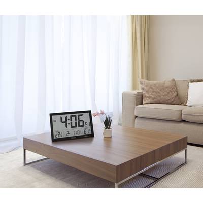 A modern, minimalist living room view featuring a coffee table displaying a digital clock showing '4:06 PM'.