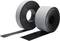 Two rolls of black, self-adhesive sealing tape with a grey surface, standing side by side with a section of tape unrolled.