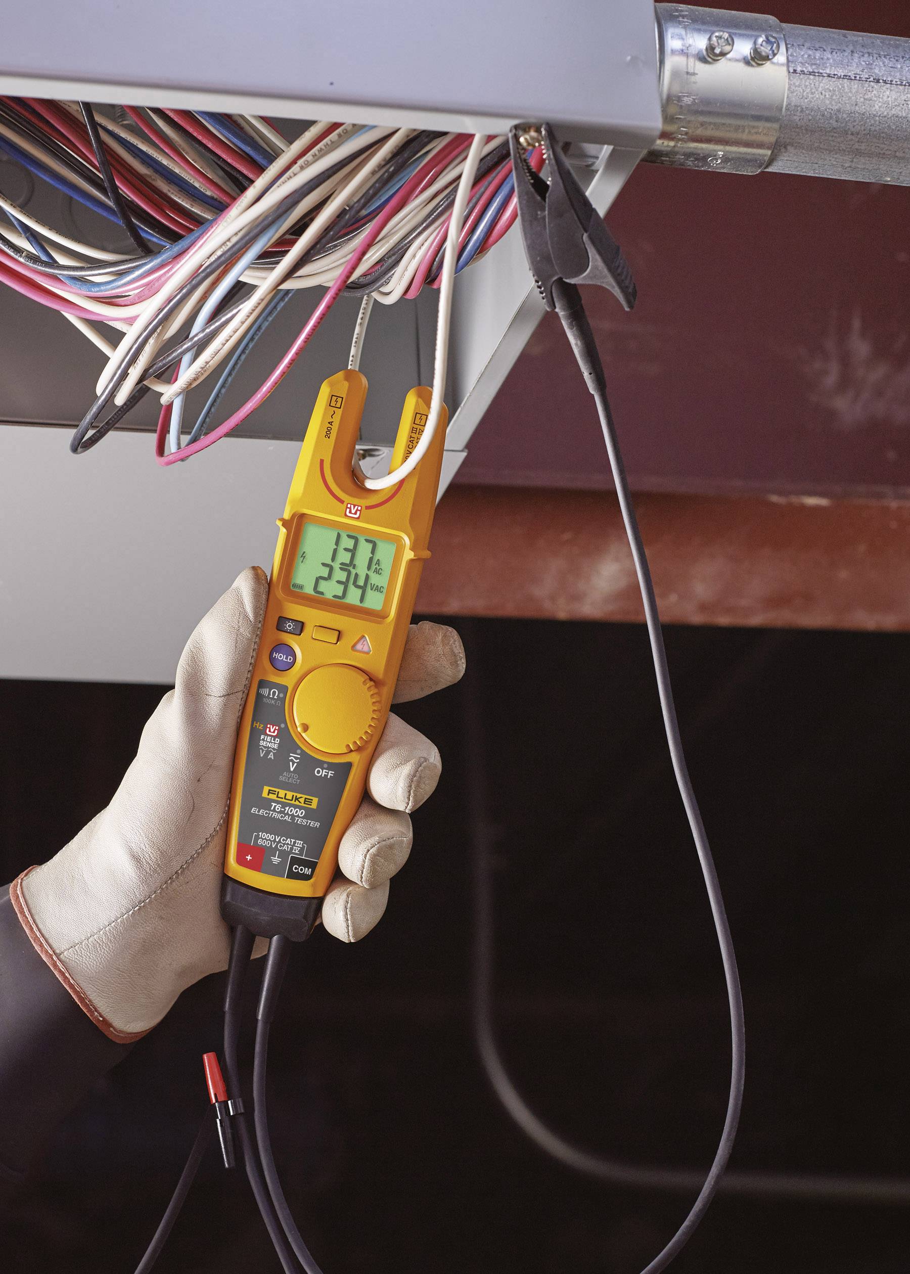 'An electrician is measuring voltage on a switchboard using a digital multimeter. The display reading shows 234 volts.'