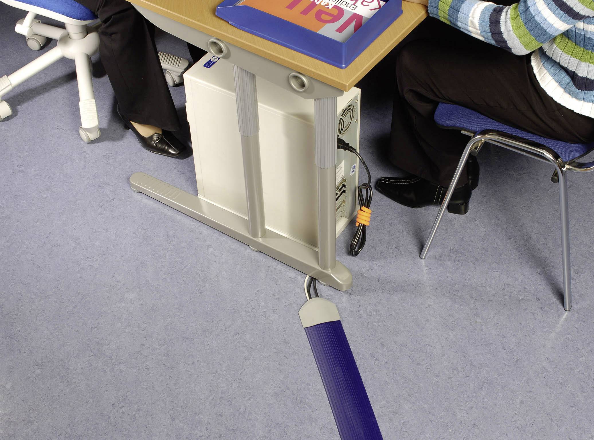 Two people are sitting at a desk with a computer. A cable management system keeps the cables neatly organised underneath the table.