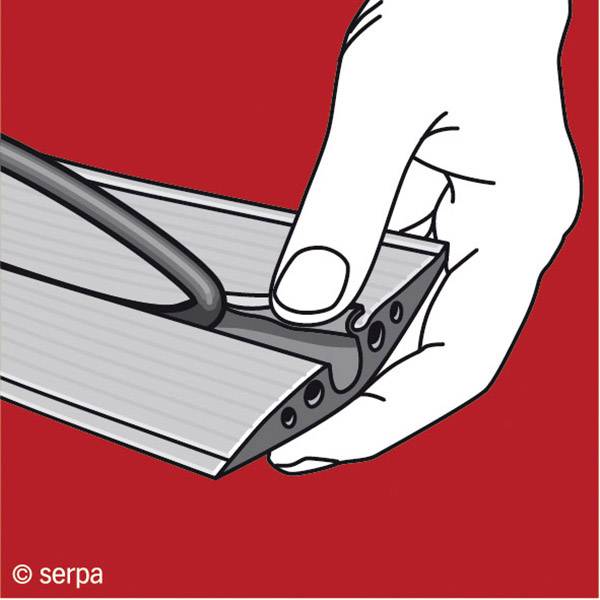 A hand holds an aluminium profile while a black rubber strip is being inserted into a groove. Red background.