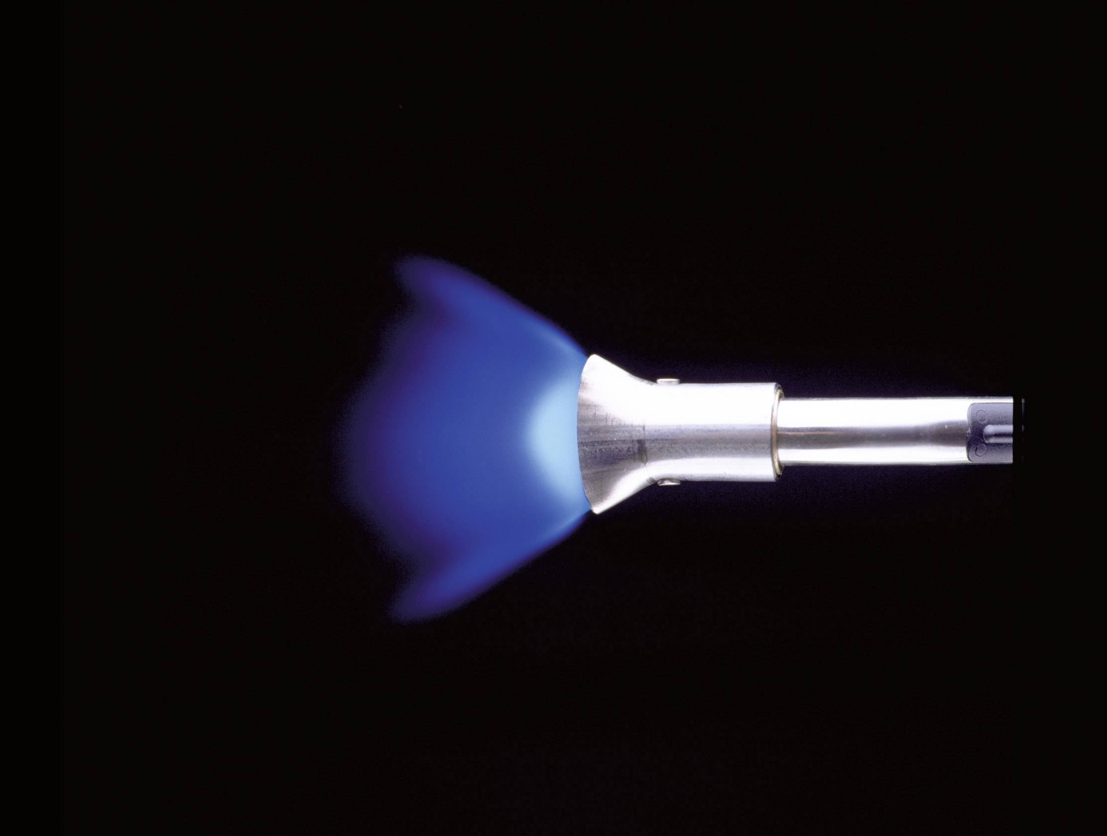 A Bunsen burner with a blue flame on a black background. The flame shows uniform combustion.