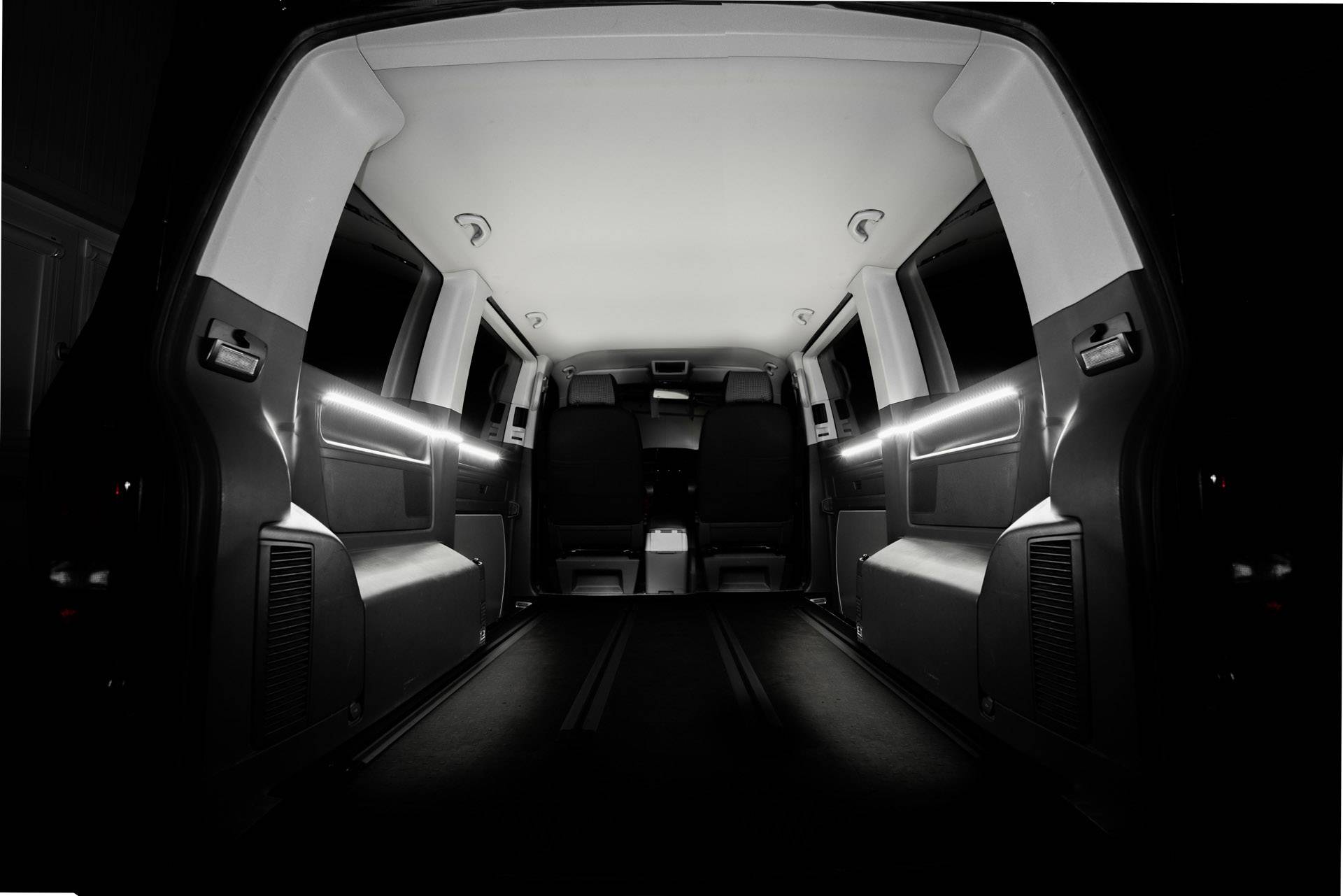 Interior view of an empty, well-lit delivery van. View from the back towards the front.