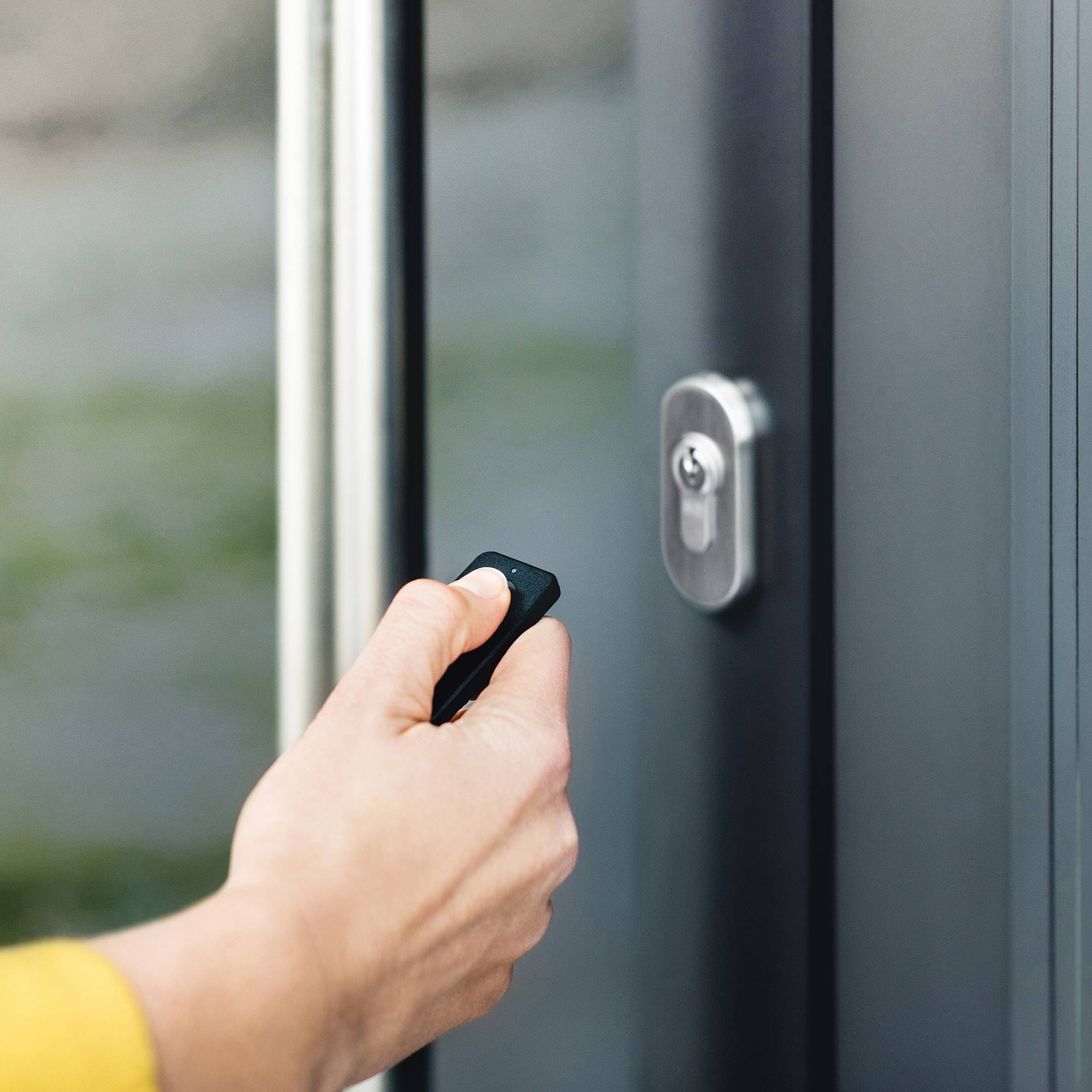 A person is holding a key in front of a door lock, ready to open the door.