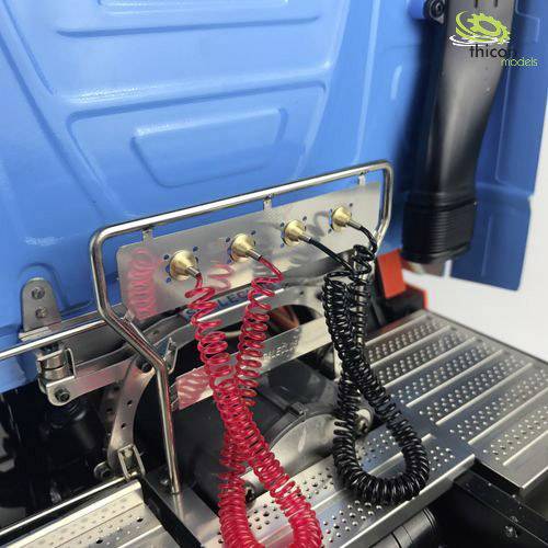 A model truck in blue, with red and black cables attached to the rear wall, reveals wiring details.