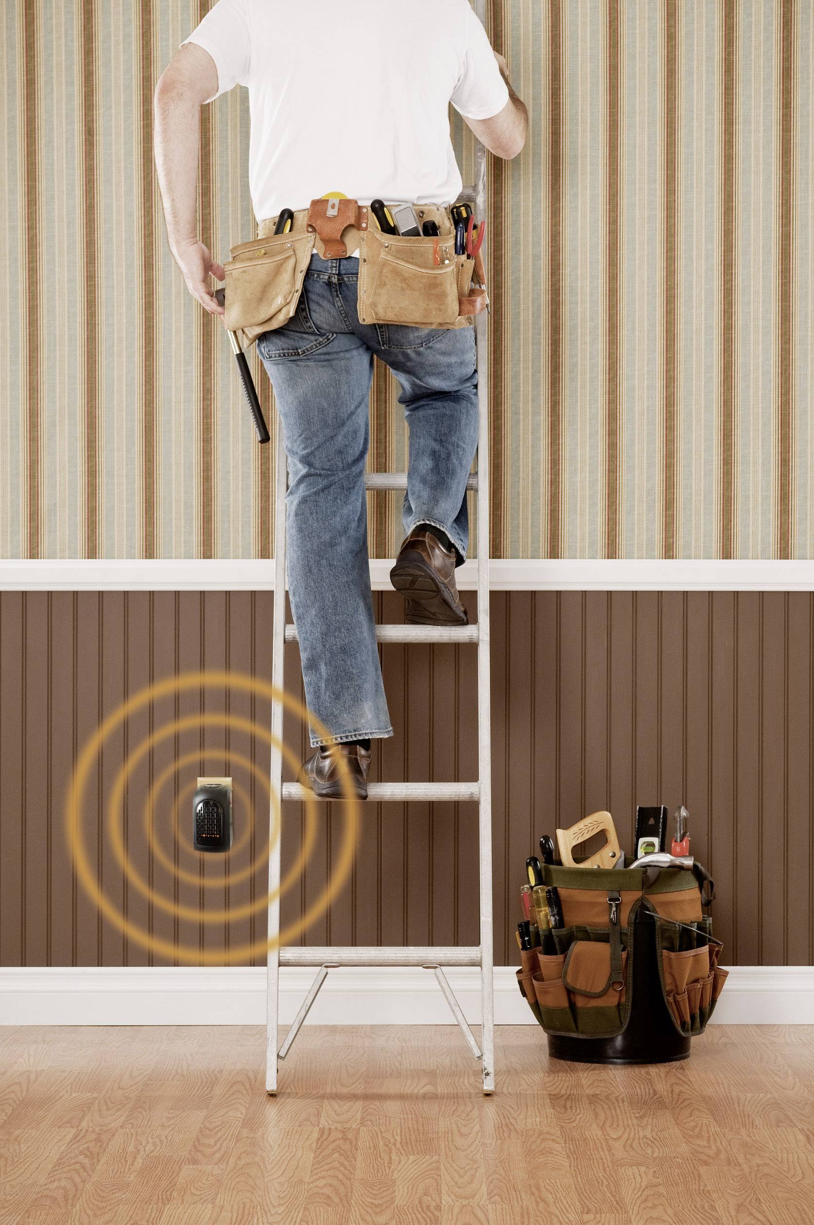 A tradesman is standing on a ladder in front of a wall. A detector with signal waves is activated. Tool bag on the floor.