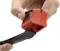 A hand is holding a red cable stripper, while another hand lifts a red cover at the tip to reveal the tool.