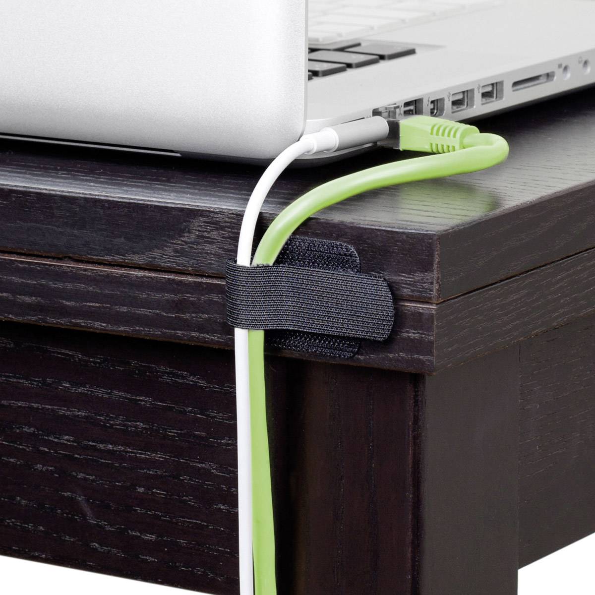 A laptop on a wooden table with cables secured by a cable management strap.