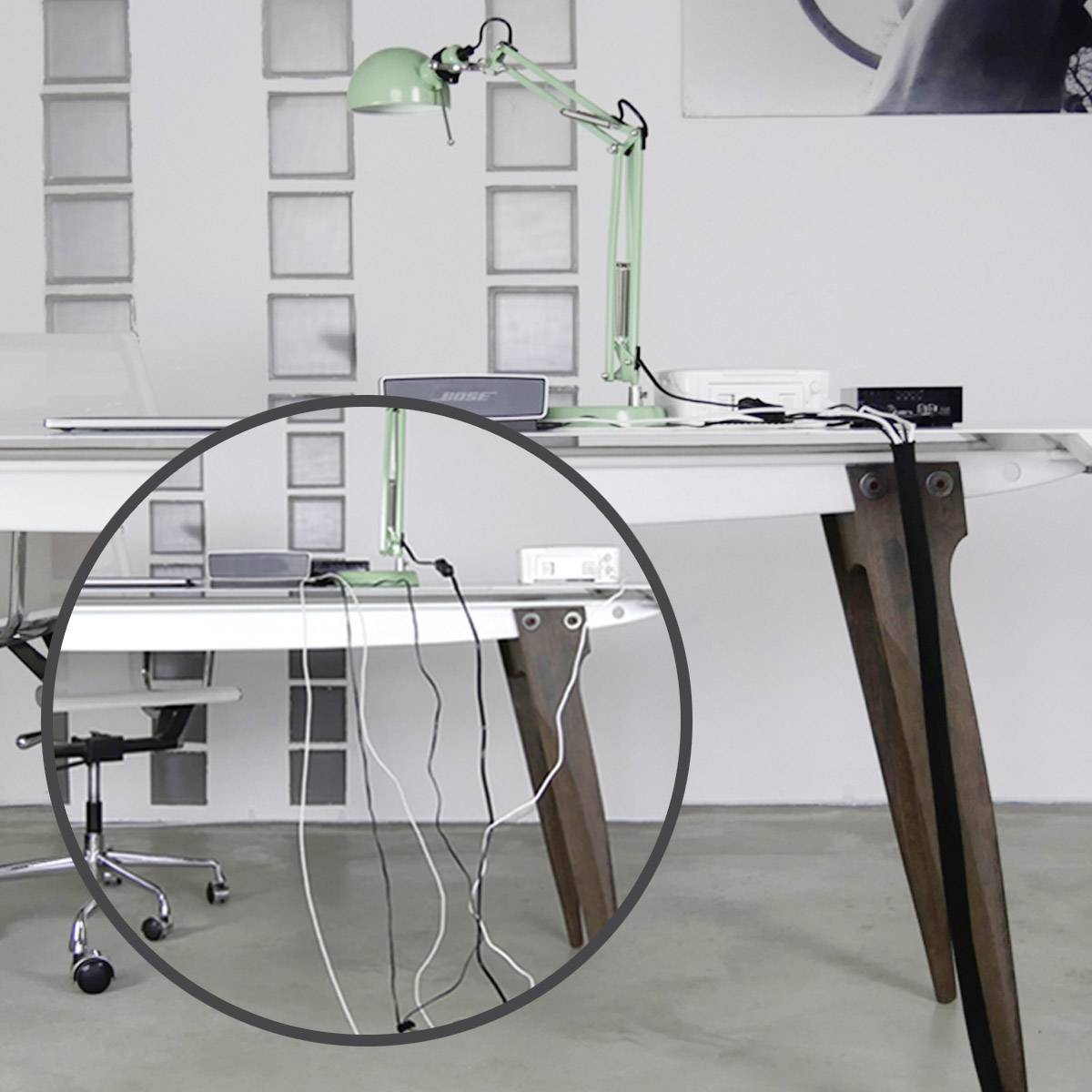 A desk with a green lamp and several electronic devices. Wires are neatly routed underneath the table.