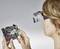 A person is examining a circuit board through magnifying lenses. They are inspecting the details of the circuit.