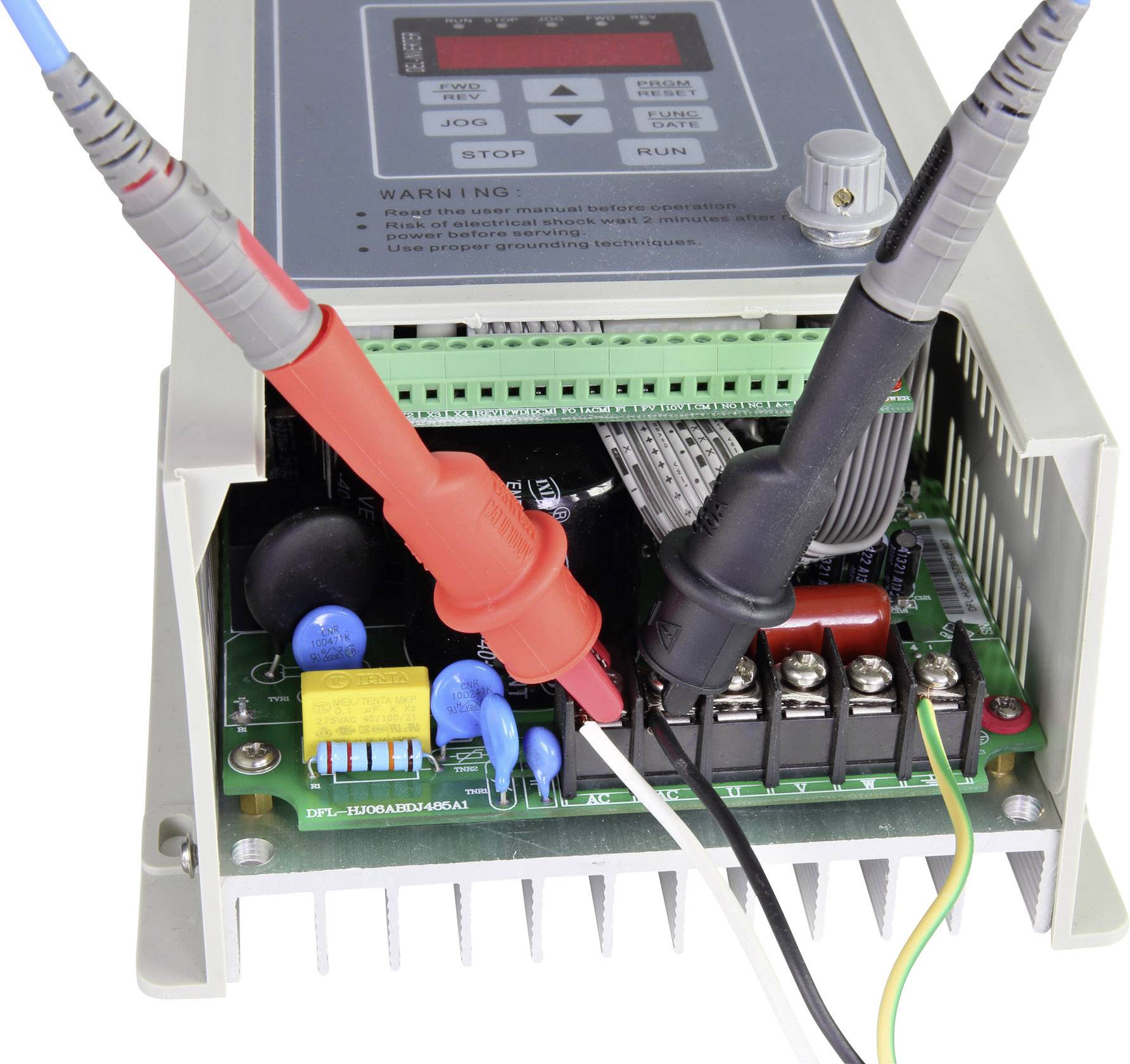 Electronic device with an open casing; shows a green motherboard with test probes connected.