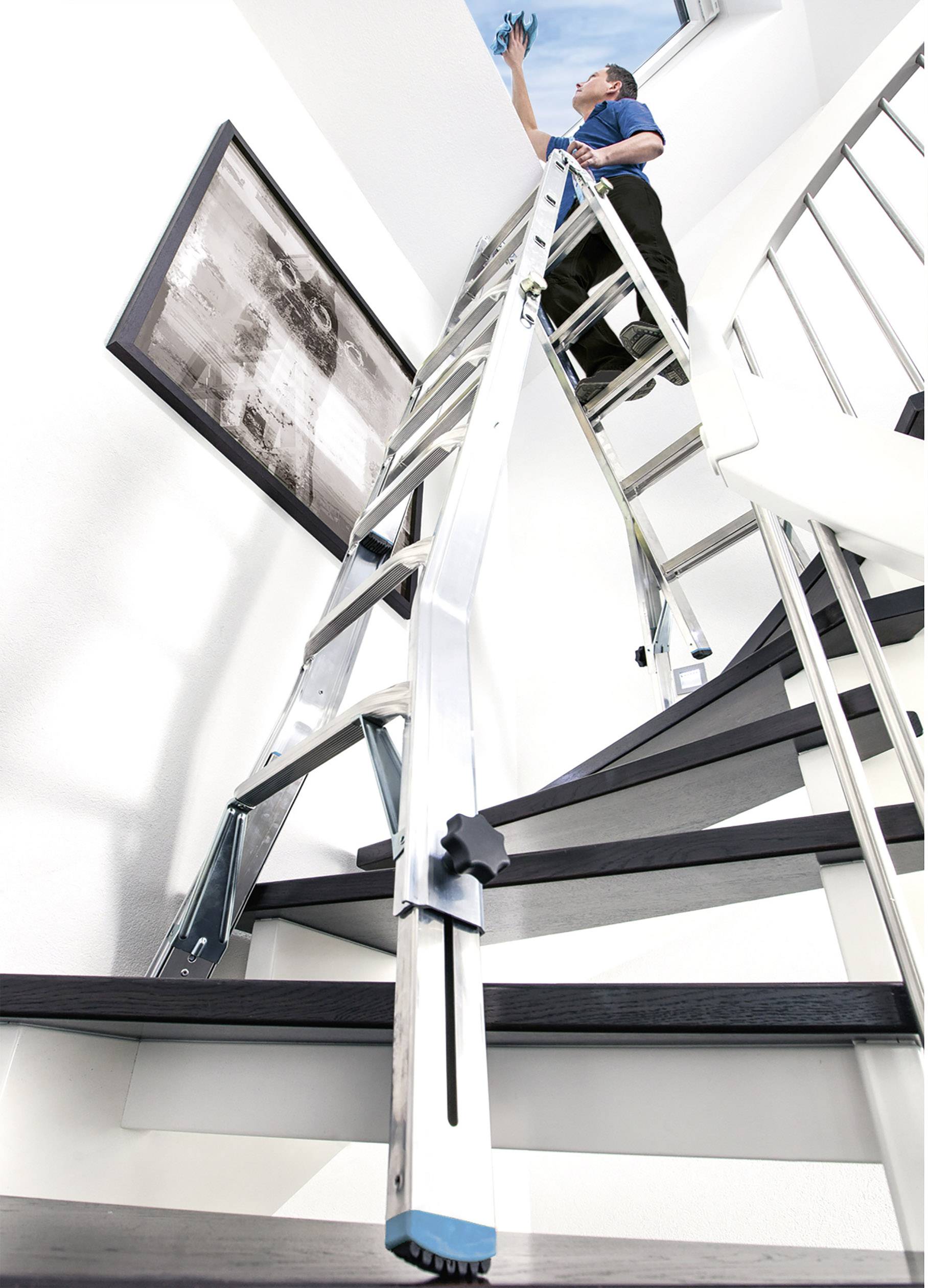 A person on a ladder is cleaning a skylight. The ladder is positioned on a staircase. A black and white photograph hangs on the wall.