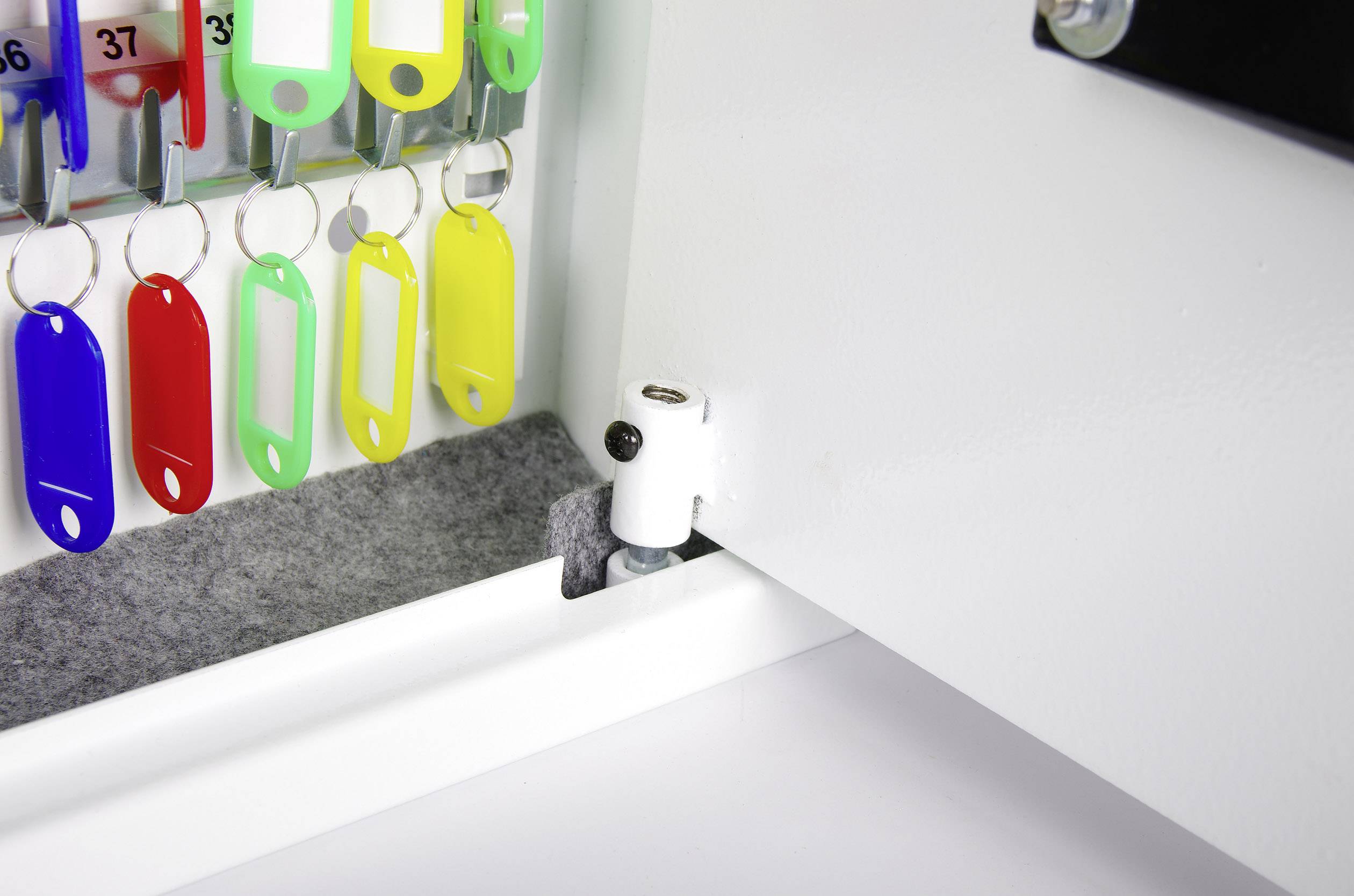 A cupboard with open doors reveals numerous colourful key rings hanging on hooks.