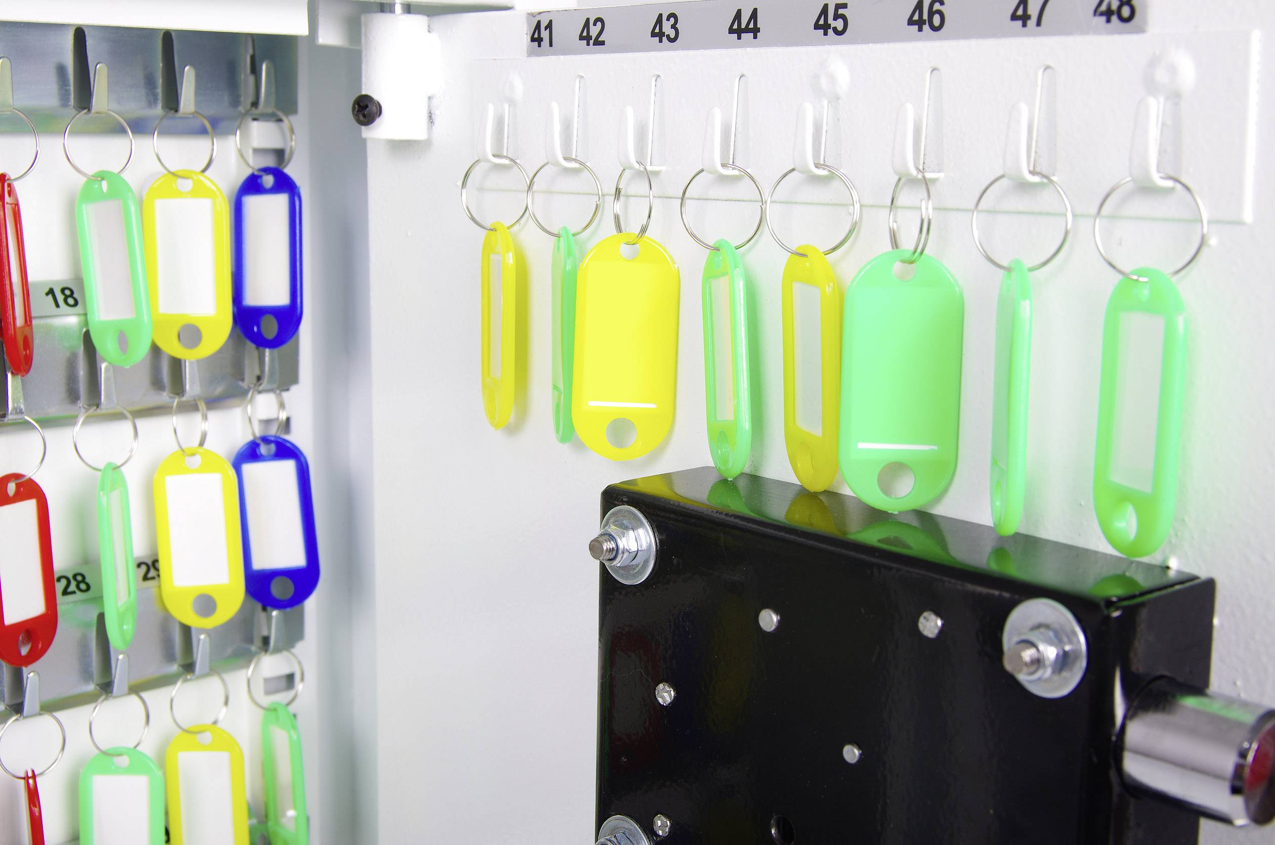 'Key fobs in various colours hang on hooks in a key management system. Numbered rows above the hooks.'