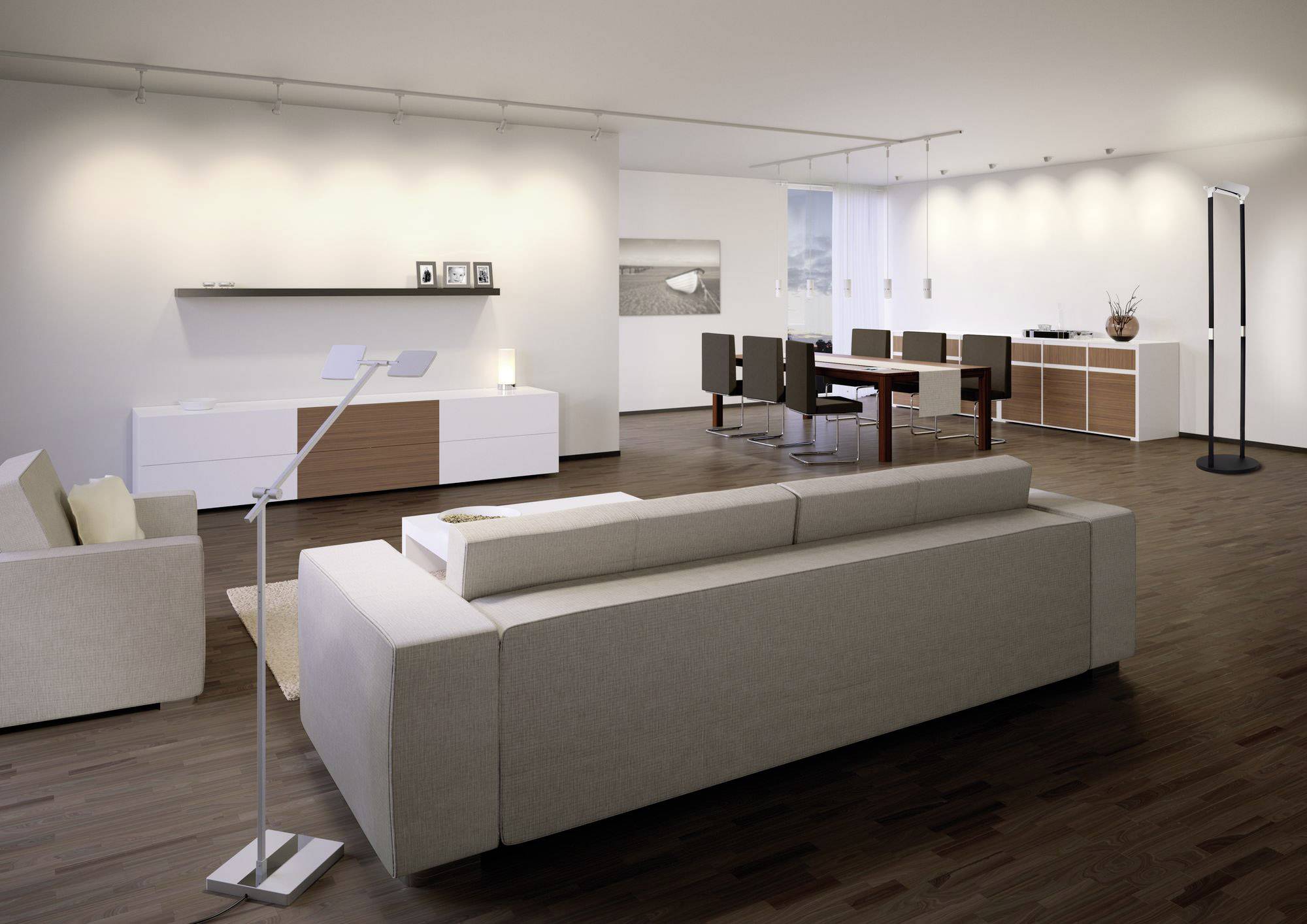 A modern living room with light walls, a beige sofa, wooden flooring, a dining table with chairs, and minimalist decor.